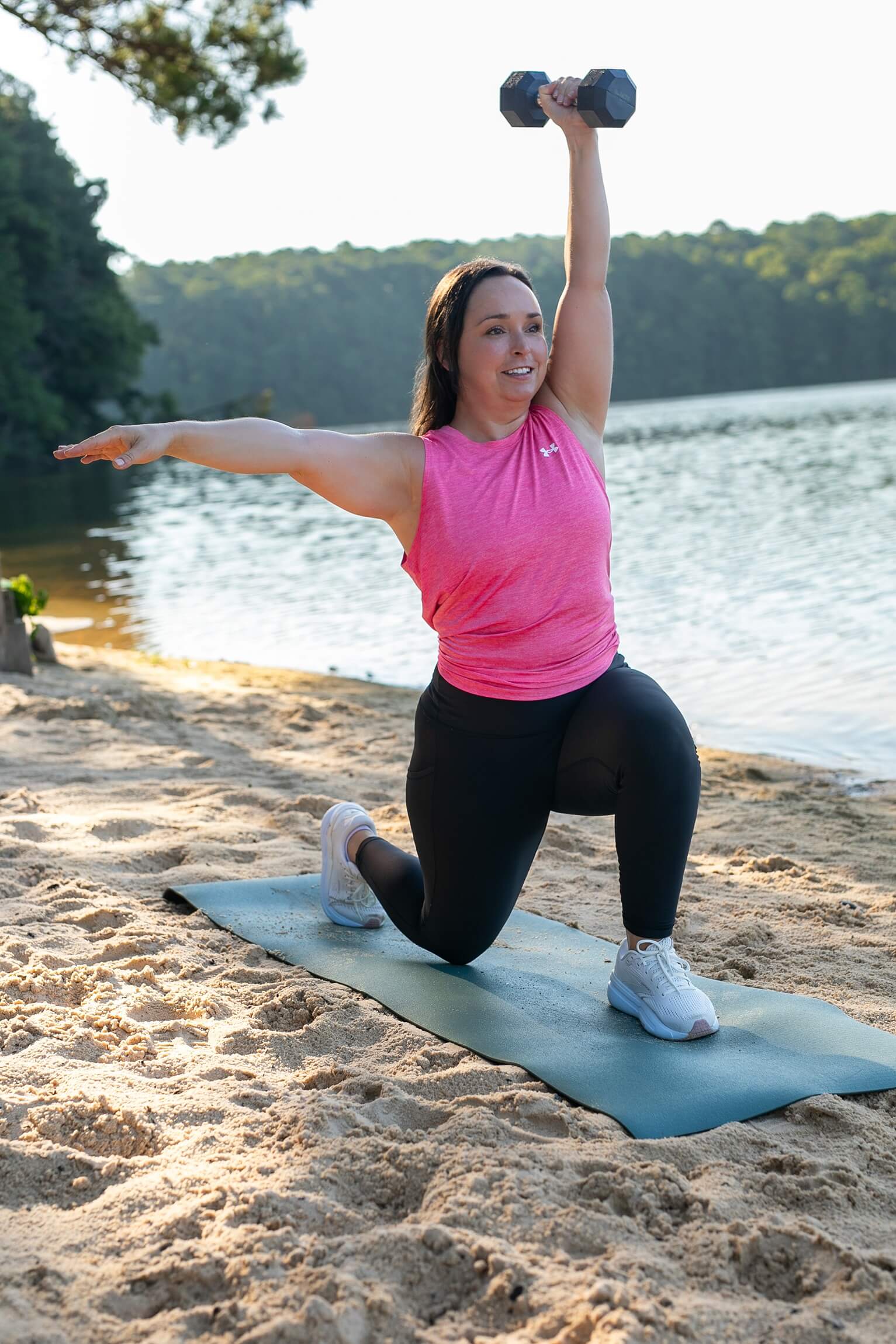 Fitness personal trainer for women, Coach Lil, working out outside doing holding weight above head in a lunge.